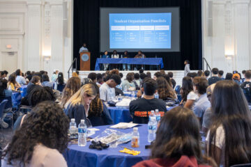 Photo of members of the CWRU community gathered at tables during a presentation during Envision Weekend