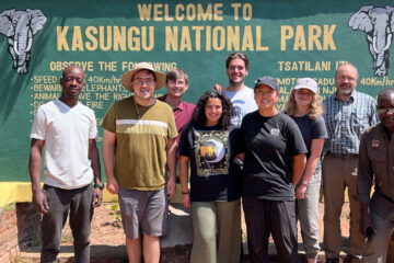 Photo of students and faculty members posing for a photo in front of a sign that says "Kasungu National Park"