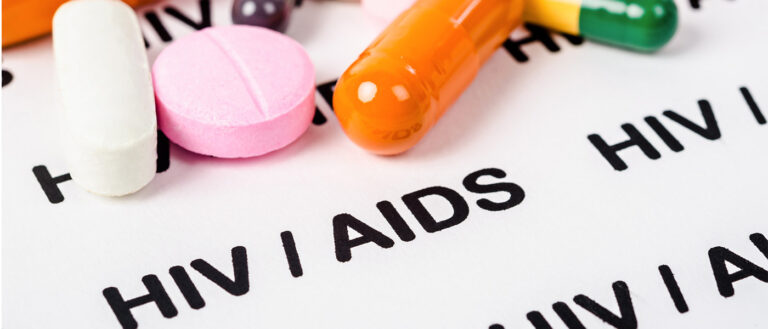 Stock image of colorful medication on a printed page reading "HIV/AIDS"