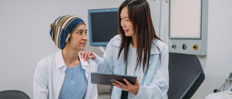 Photo of a doctor talking to a breast cancer patient while holding a tablet