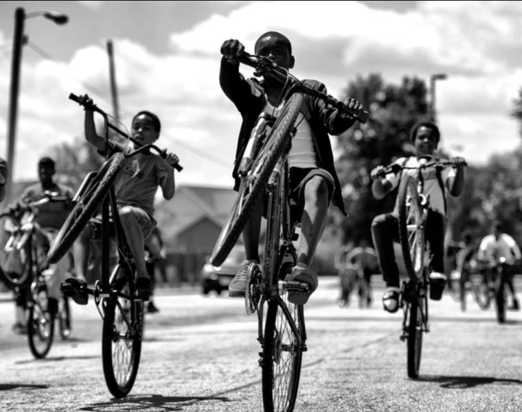 Black and white photo of African American children riding bikes. Photography by Donald Black Jr