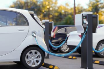 Close-up View Of Charging Electric Car In Parking Lot. Courtesy of Getty Images.