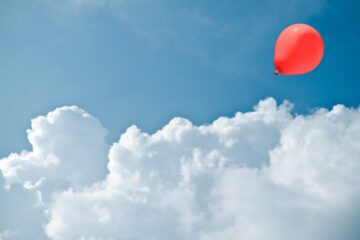 Red balloon between cloud formation. Courtesy of Getty Images.