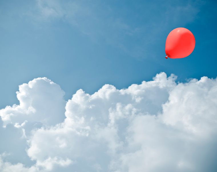 Red balloon between cloud formation. Courtesy of Getty Images.
