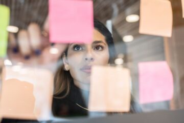Phot of a young woman writing in post it at the office. Courtesy of Getty Images.