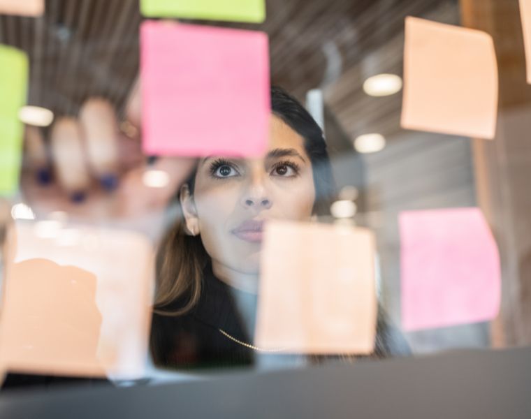 Phot of a young woman writing in post it at the office. Courtesy of Getty Images.