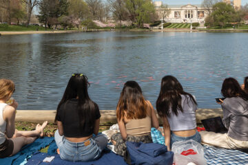 Rear view of a group of women sitting outside near a lake.