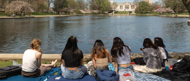Rear view of a group of women sitting outside near a lake.