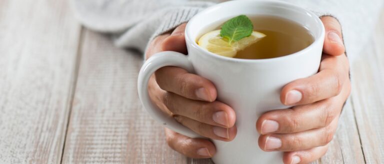 Close up of a woman holding a mug with herbal tea. Courtesy of Getty Images.