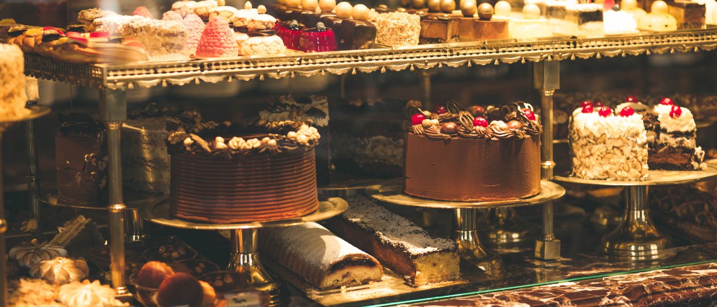 Photo of a pastry shop display window with variety of cakes. Courtesy of Getty Images