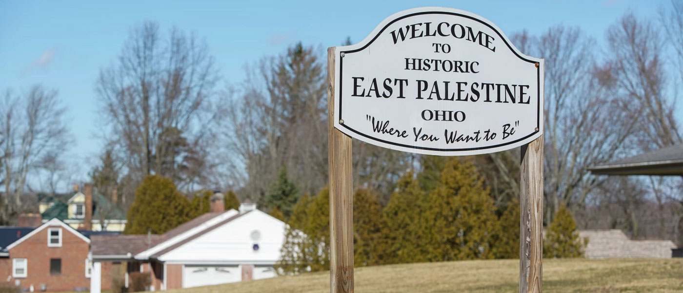 Photo of the East Palestine welcome sign with residential houses in the background