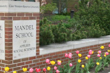 Photo of tulips blooming in front of the Jack, Joseph and Morton Mandel School of Applied Social Sciences sign