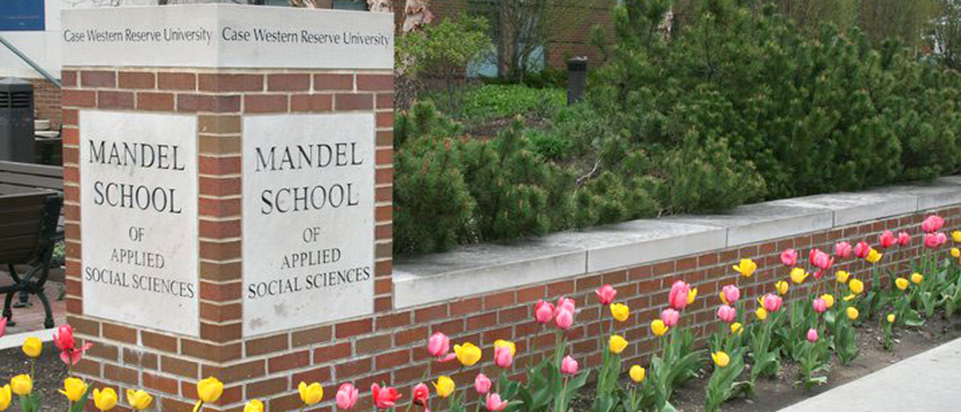 Photo of tulips blooming in front of the Jack, Joseph and Morton Mandel School of Applied Social Sciences sign