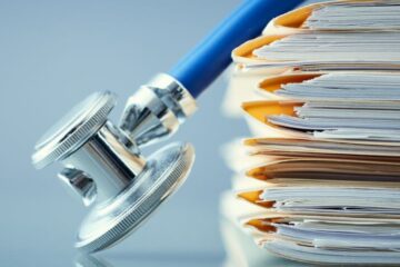 Close up of a stack of medical records and a stethoscope