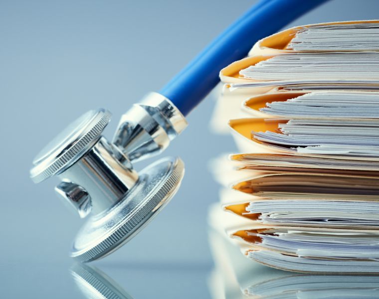 Close up of a stack of medical records and a stethoscope
