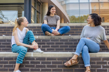 Photo of three CWRU Mandel School students sitting together outside on campus