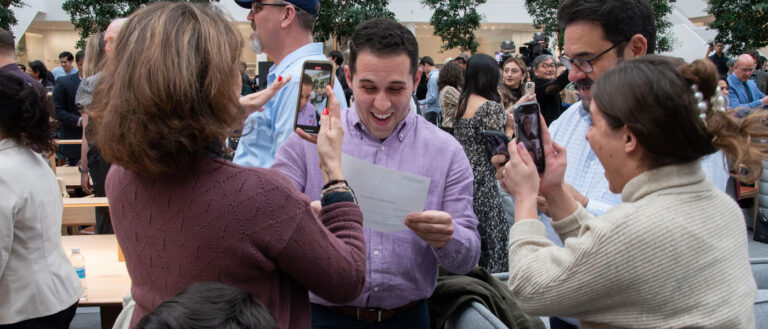 Photo of a CWRU med student opening his match day envelope in excitement as family surrounds them in celebration