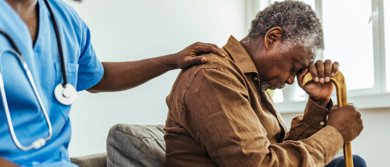 Caregiver consoling a senior male patient in a nursing home during the day