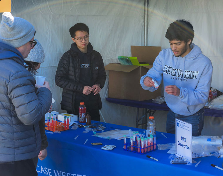 CWRU students volunteering working a booth teaching kids to extract their DNA and making a necklace with it during an eclipse event