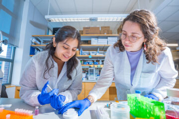 Photo of two researchers in Agata Exner's lab working at a bench injecting a substance into a petri dish