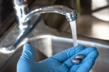 Lead metal hold in hand in front of tap water. Courtesy of Getty Images.