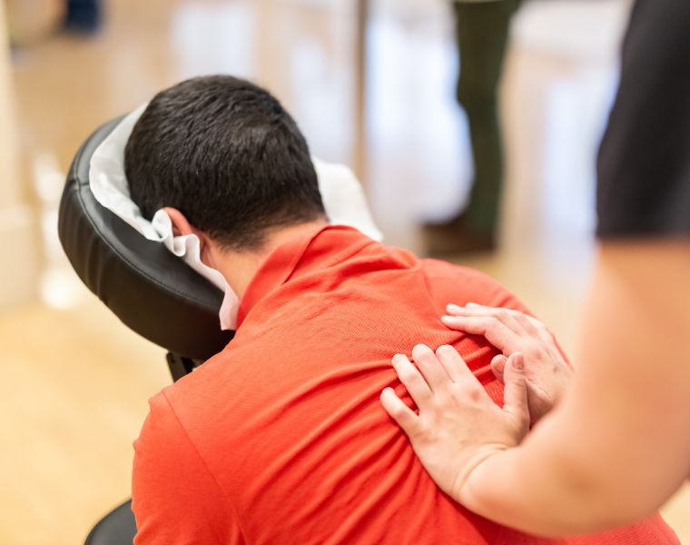 Man seated in a massage chair for back massage. Courtesy of Getty Images.