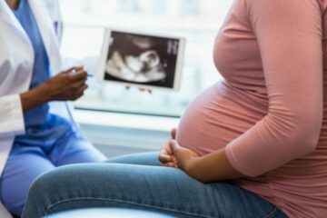 Close up of a pregnant woman and doctor with a photo of an ultrasound in the background. Courtesy of Getty Images.