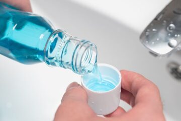 Close up of hands pouring mouthwash into cap. Courtesy of Getty Images.