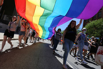 Photo taken from below as members of the CWRU community carry a rainbow pride flag