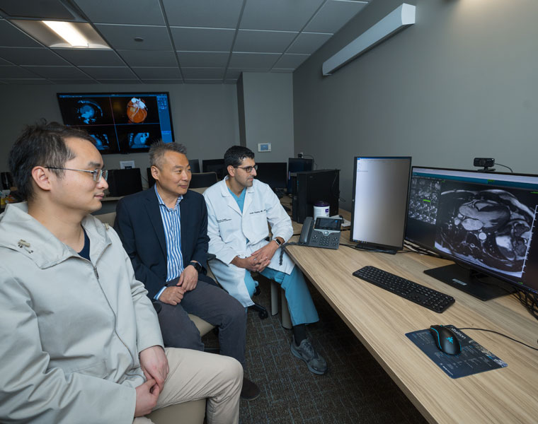 Photo of Shuo Li and two members of his research team looking at medical imaging on a computer screen