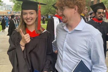 Photo of a happy CWRU graduate giving the thumbs up while posing with a guest.
