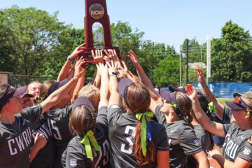 Case Western Reserve University softball players huddle together and hold up an NCAA trophy