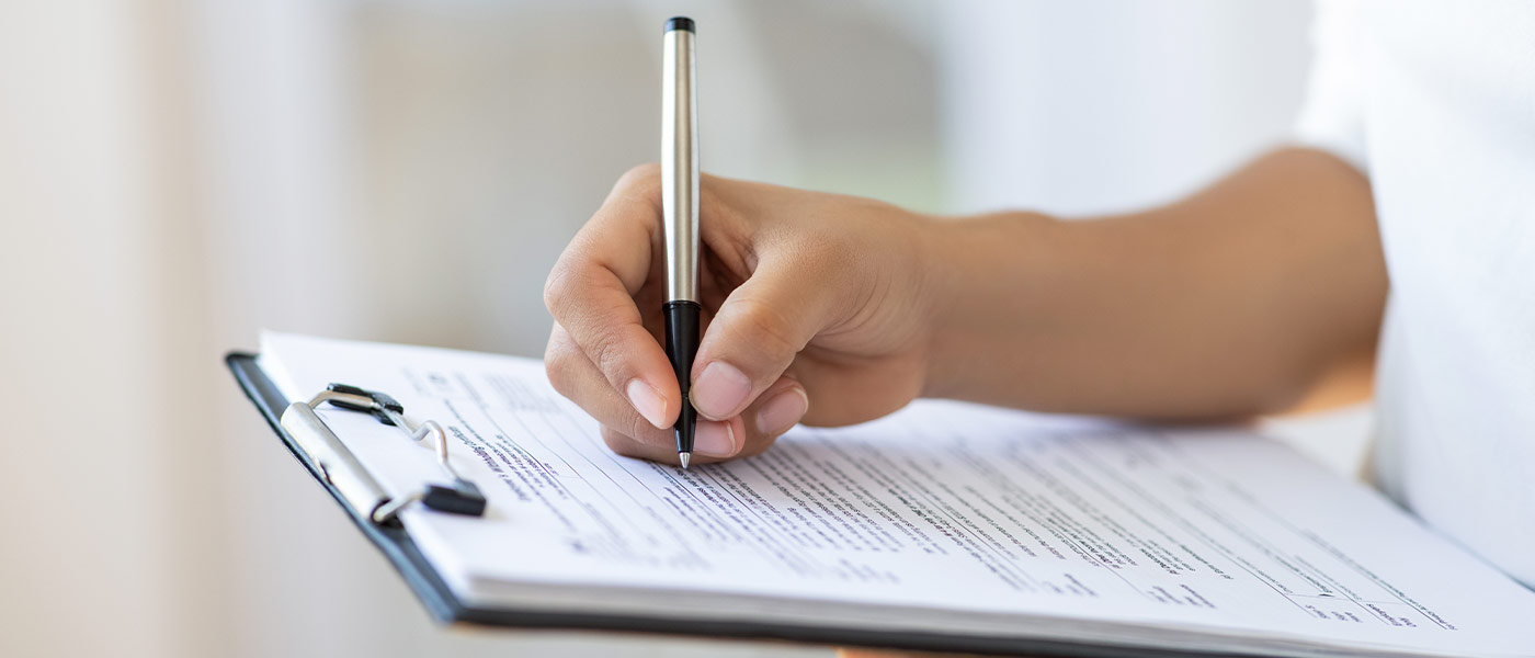 someone filling out a medical form with a black pen on white paper with a clipboard to assess violence