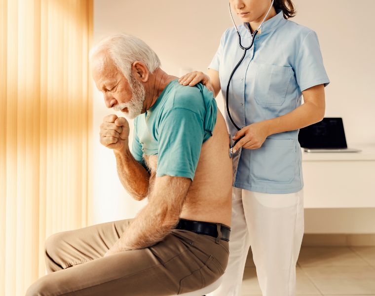 Photo of a sick old man coughing and getting medical attention by a female doctor.