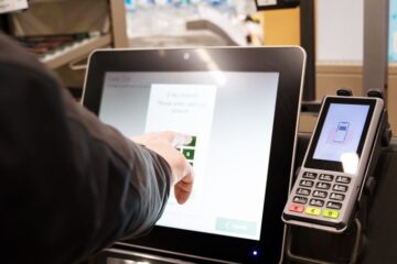 Close up of a shopper using a self-check out kiosk. Courtesy of Getty Images.