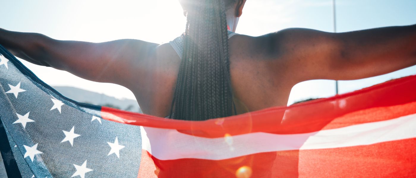 Back view of an athlete holding the American flag during a sports event. Courtesy of Getty Images.