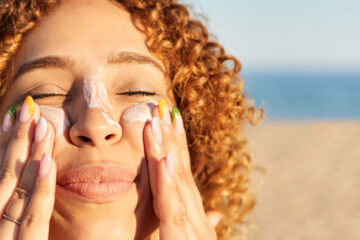 Close up photo on a young woman's face as she applies sunscreen