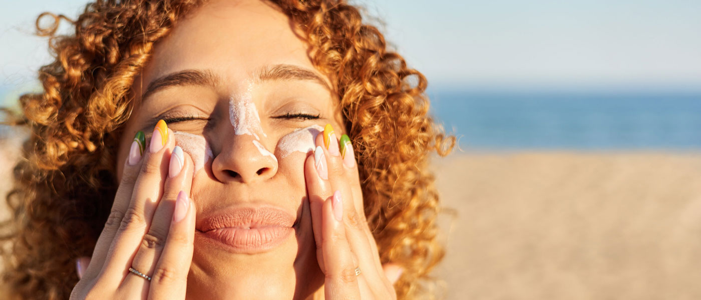 Close up photo on a young woman's face as she applies sunscreen