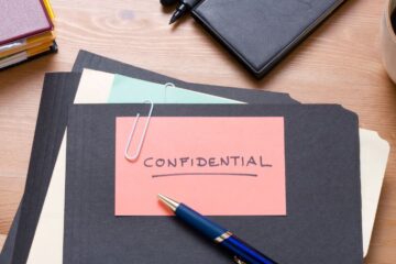 Close up of a desk top with file folders and a note that reads 'confidential'. Photography by Getty Images.