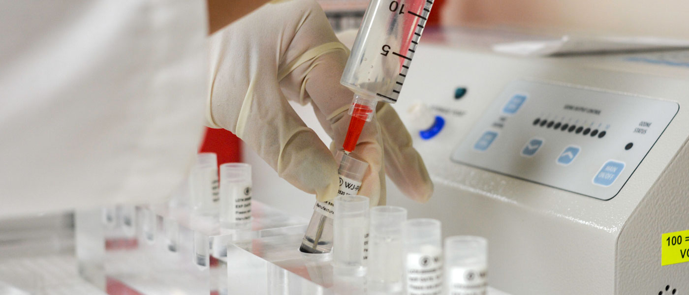 Close up photo of a doctor drawing up mesenchymal stem cells from vials on counter into syringe