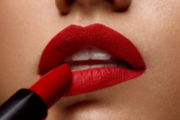 Closeup of woman putting on red lipstick.