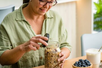 Photo of a woman preparing healthy vegan breakfast with oatmeal , honey, berries, seeds, and fruits. Courtesy of Getty Images.