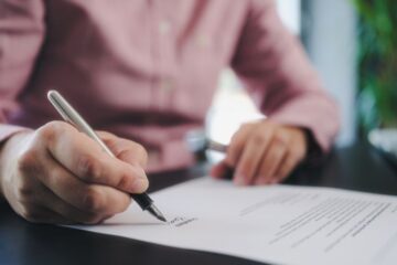 Photo of an individual signing an official document. Courtesy of Getty Images.