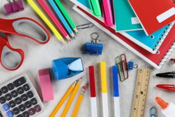 Overhead view of an assortment of school supplies on a table. Courtesy of Getty Images.