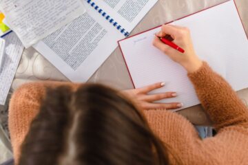 A young woman sitting at a desk in her home, earnestly studying for an upcoming exam. Courtesy of Getty Images.