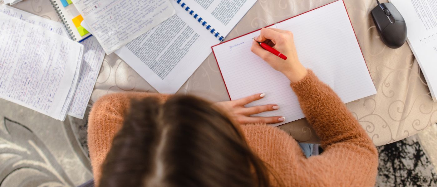 A young woman sitting at a desk in her home, earnestly studying for an upcoming exam. Courtesy of Getty Images.