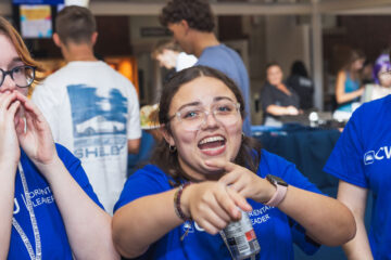 Photo of students singing and dancing while wearing blue CWRU gear