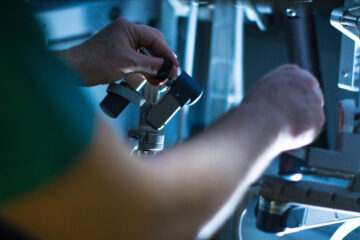 Close up photo showing a surgeon's arms and hands working on precision surgery using a robot