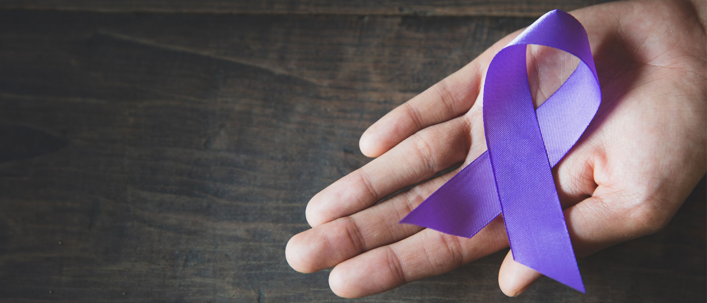 Photo of a hand holding a purple ribbon