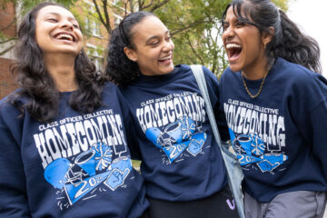 Photo of three smiling and laughing students posing for a photo during homecoming festivities